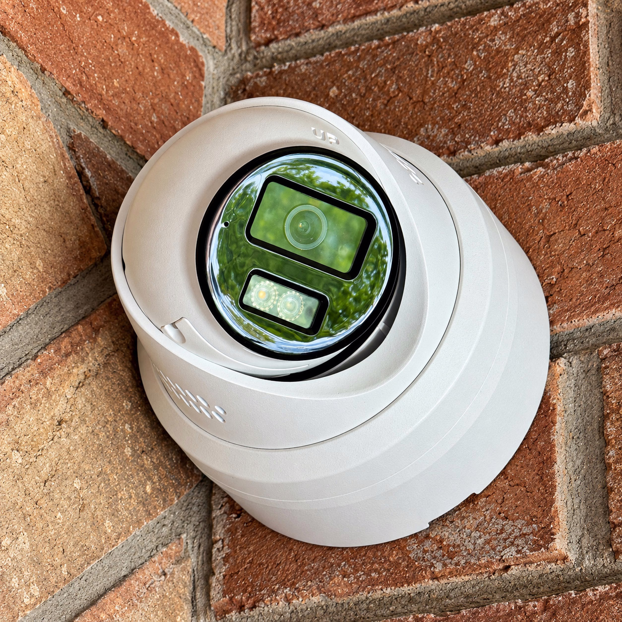 White residential security camera mounted on a brick corner