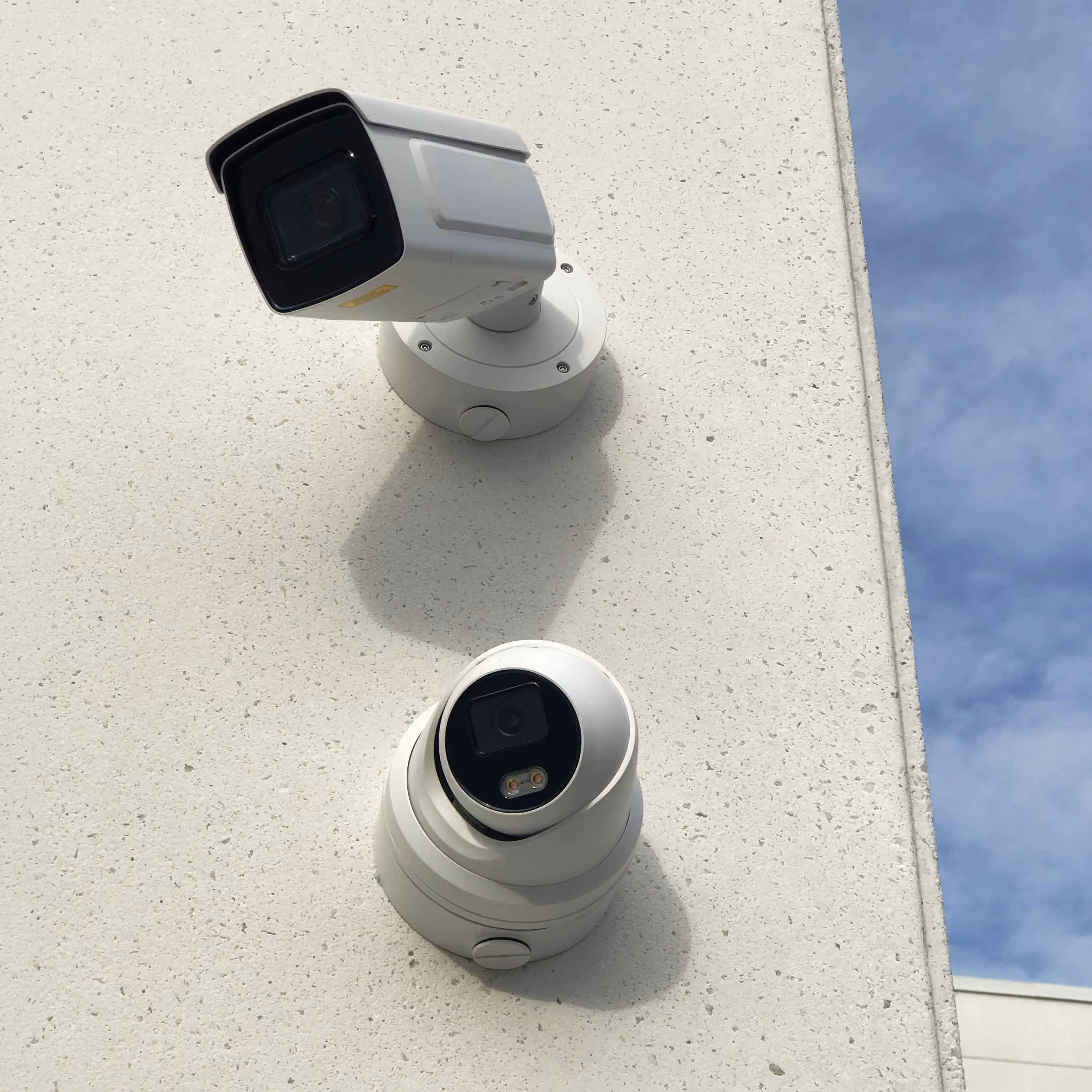 Two commercial security cameras mounted on an exterior wall