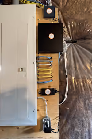 Security equipment and neatly routed network cables mounted beside an electrical panel.