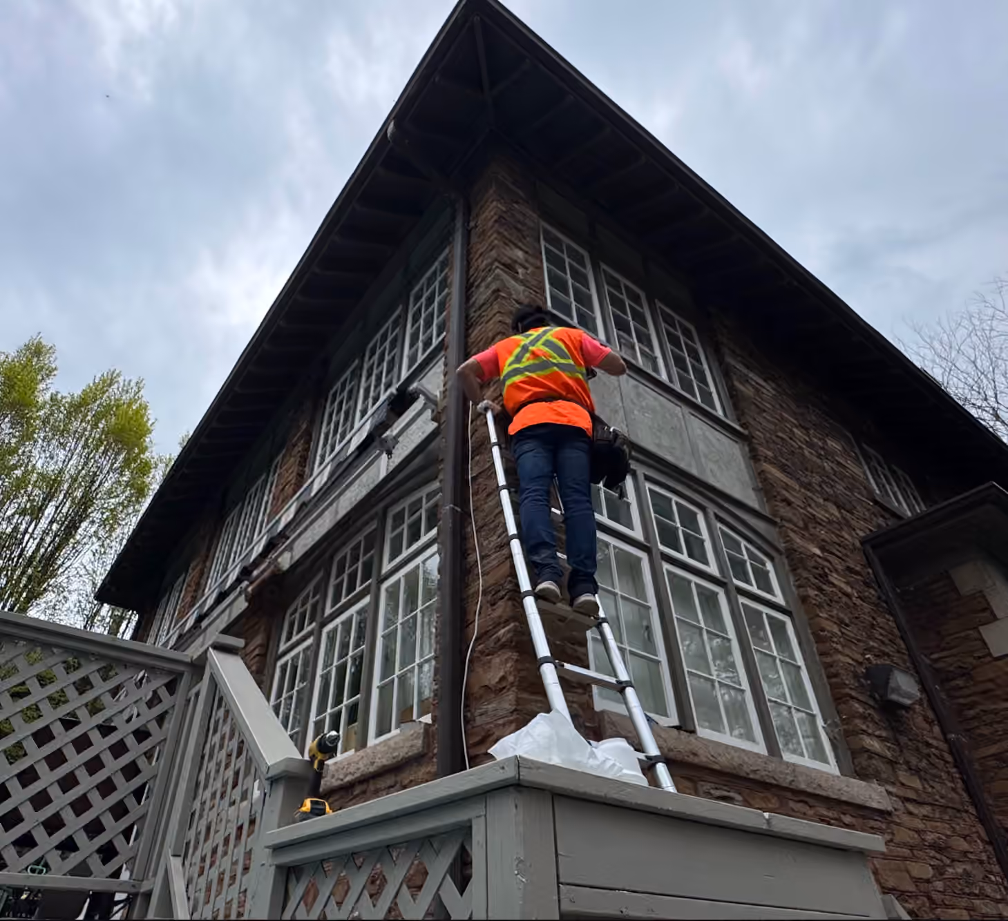 Technician installing outdoor security equipment from a ladder