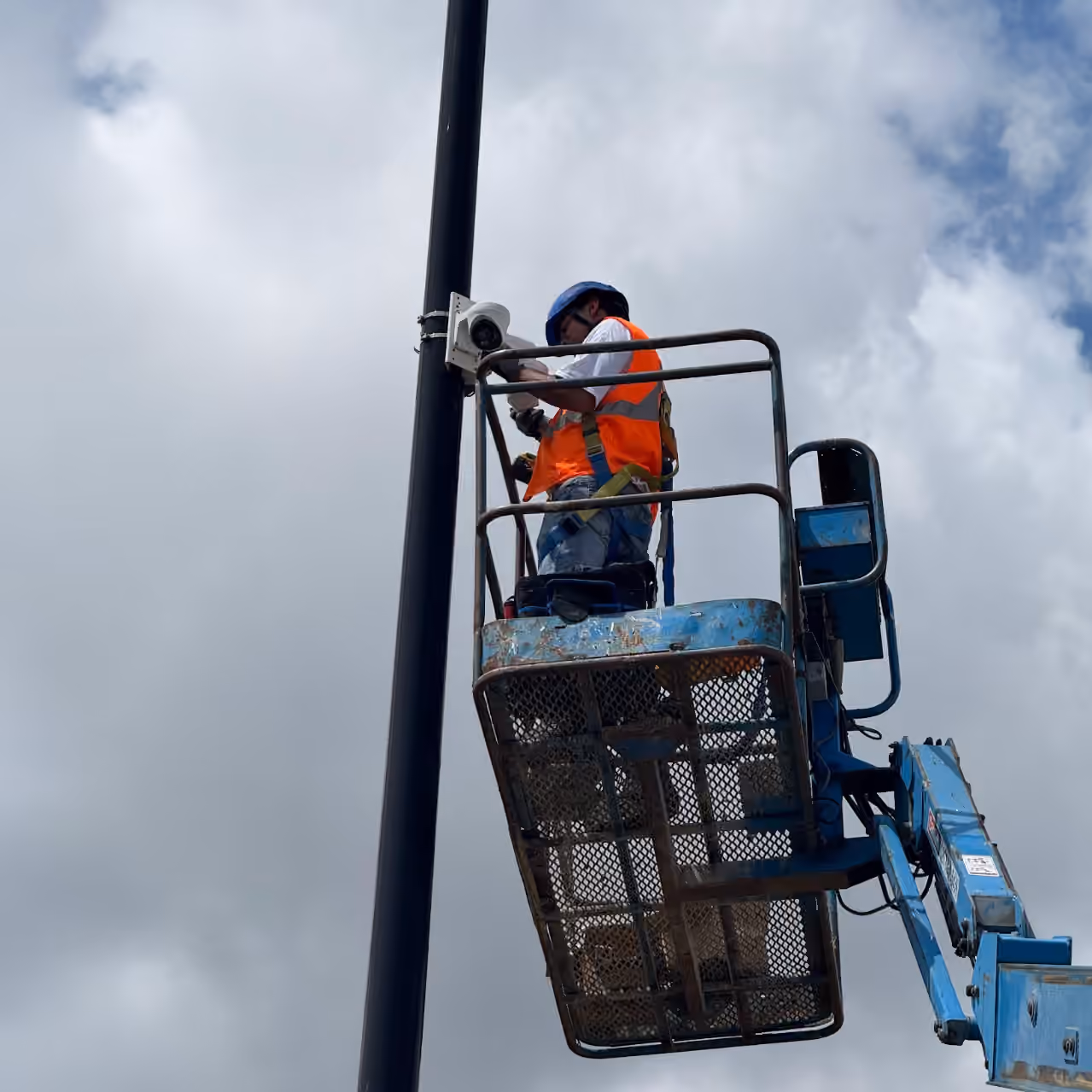 Technician working on a pole mounted security camera from a lift