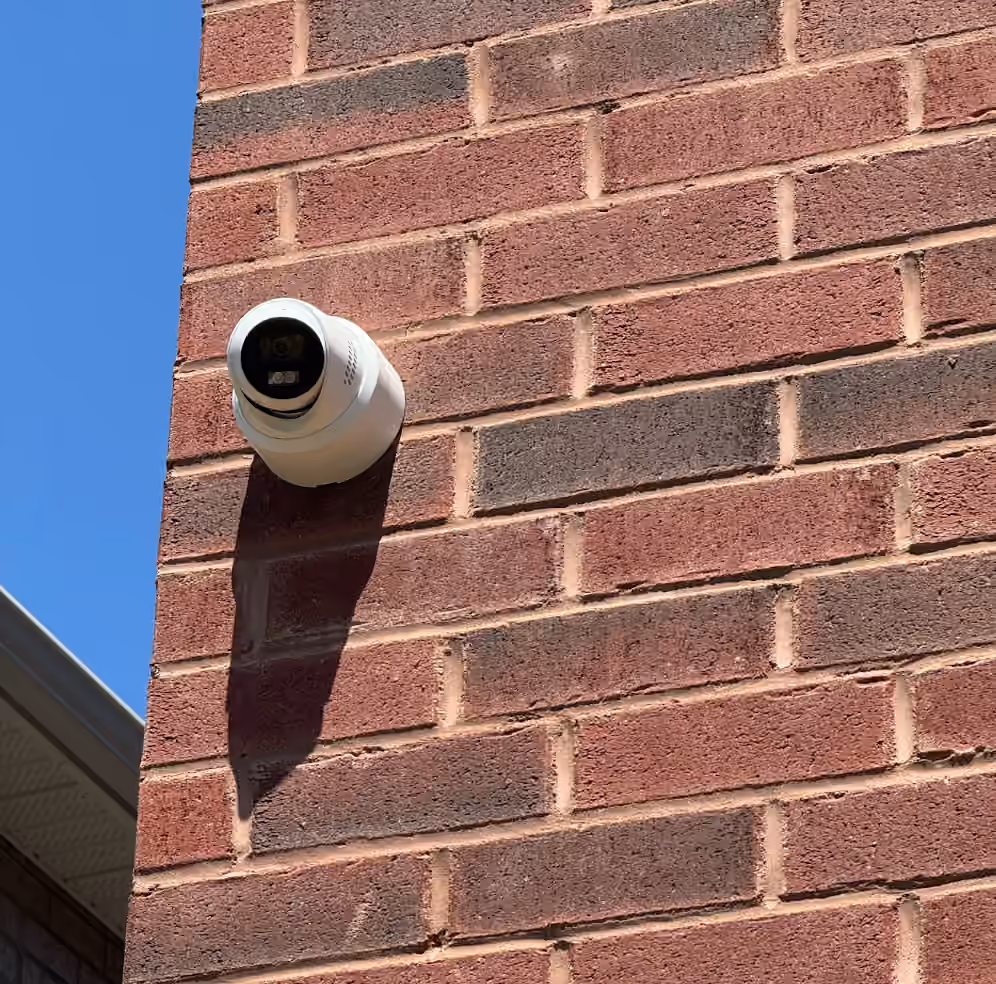 Outdoor security camera mounted on a red brick exterior wall