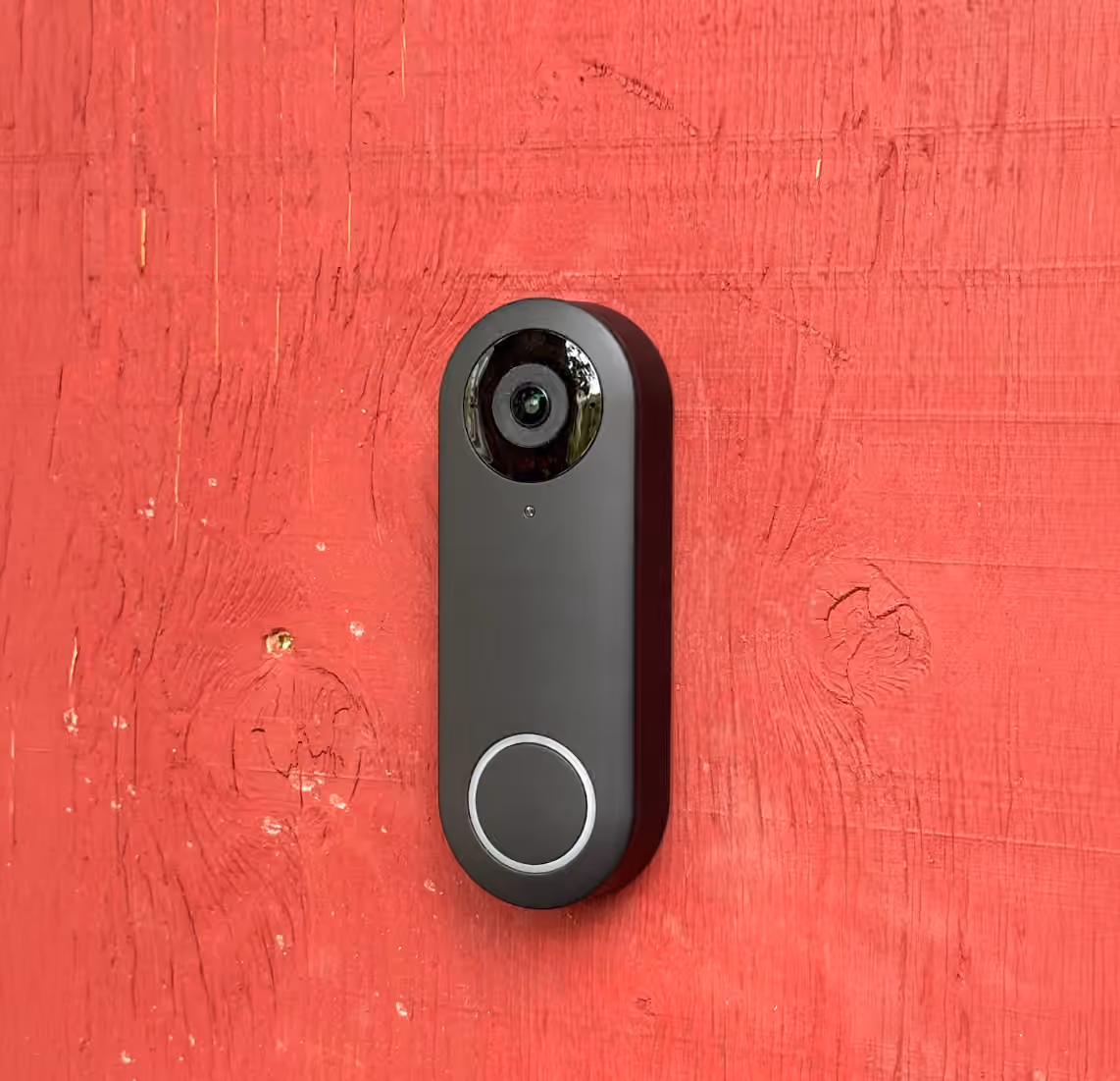 Black video doorbell mounted on a red wall