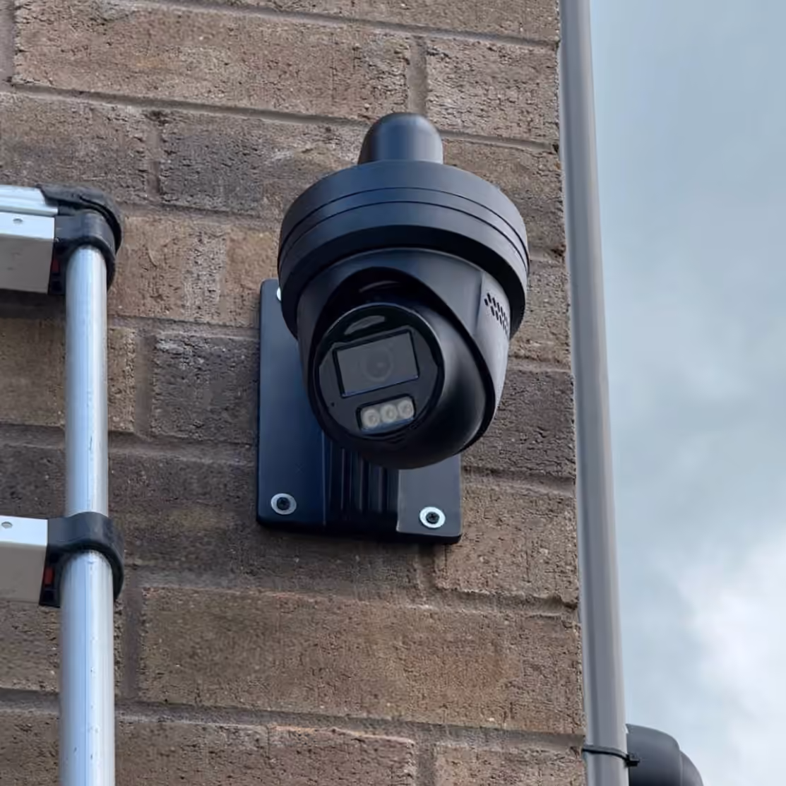 Black security camera mounted on an exterior brick wall