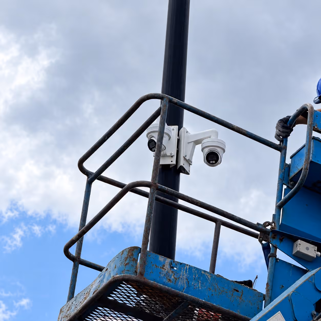 Commercial camera installation from a lift beside a tall pole