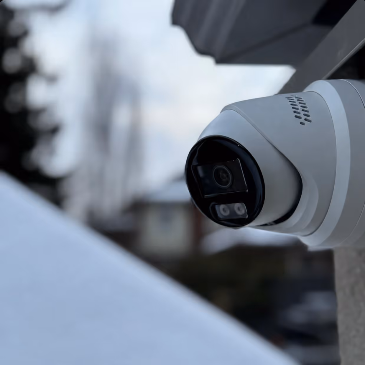 Outdoor turret security camera installed under an exterior roofline