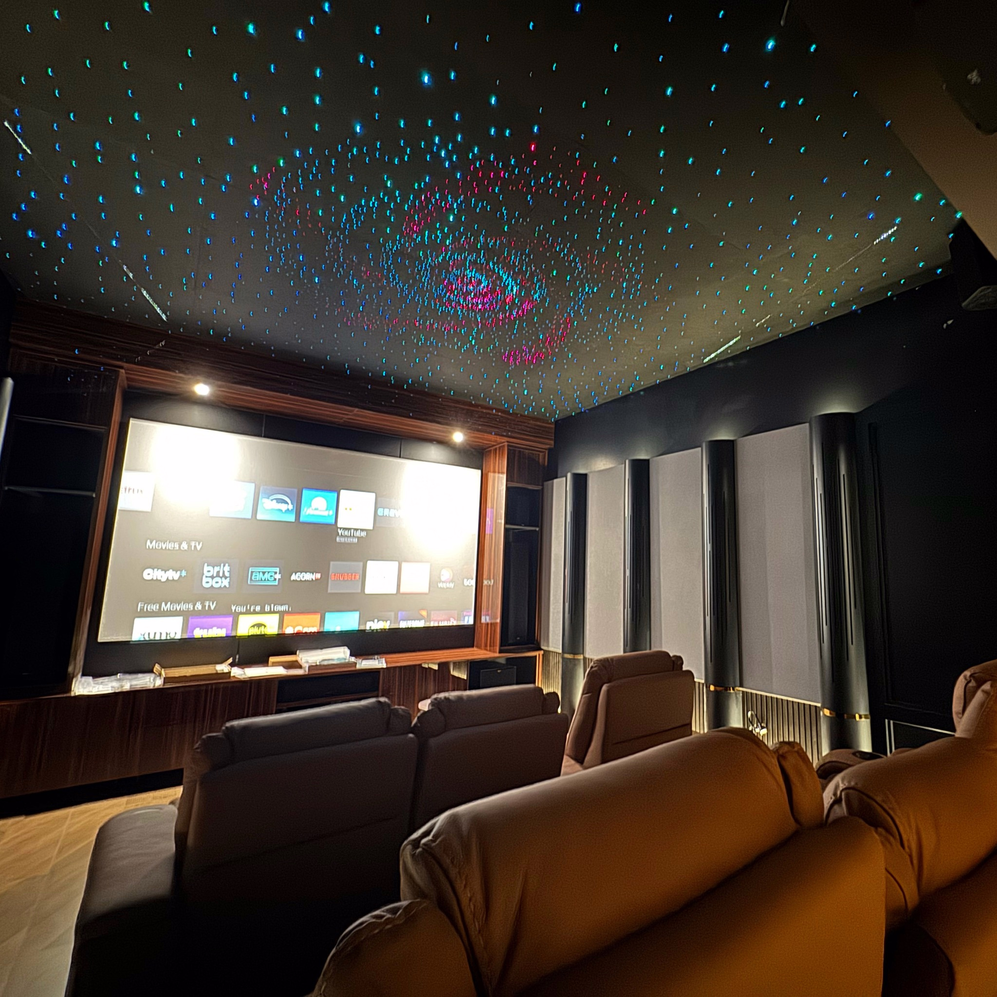 Home theatre with a projection screen, acoustic wall panels, and a star-lit ceiling