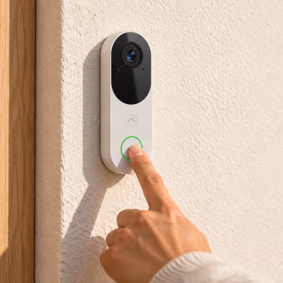 Hand pressing a video doorbell beside a home entrance