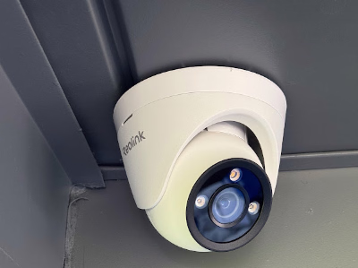 White Reolink turret camera mounted beneath an overhang.